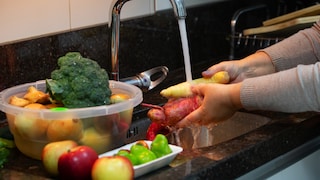 Jemand wächst Obst und Gemüse unter fließendem Wasser