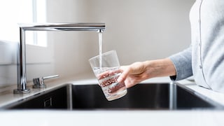 Jemand schenkt Leitungswasser in Glas ein