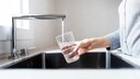 Jemand schenkt Leitungswasser in Glas ein