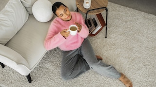 Frau mit Kaffee auf waschbarem Teppich. Gut auch, falls sie den Kaffee verschüttet