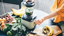 Entsafter mit viel Gemüse und Obst auf dem Tisch