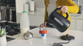 Frau schenkt mir Wasserkocher Wasser in eine Tasse ein