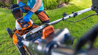 Orangefarbener Akku-Rasenmäher im Garten