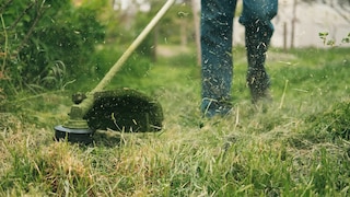 Mann mit Rasentrimmer im Garten