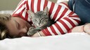 Eine schlafende Frau hält ihre Katze im Arm