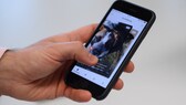 Ein Mann wischt mit seinem Daumen ein Foto in der App „Find Us“, Tiere aus dem Tierheim nach Tinder-Prinzip, beiseite.