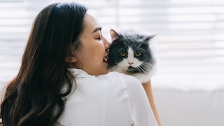 Eine junge Frau hält eine Katze fest, die sie nicht mag