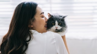 Eine junge Frau hält eine Katze fest, die sie nicht mag