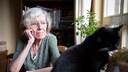 Eine ältere Frau sitzt mit ihrer Katze am Fenster