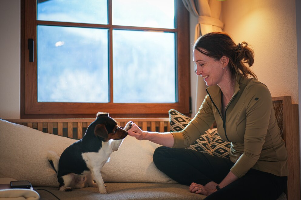 Sophie Lübbert auf einem Sofa mit Hund Sam, der ihr High-Five gibt