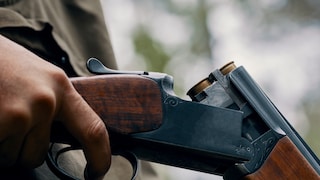 Hand eines Jägers, der ein Gewehr zum Nachladen öffnet
