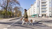 Junge Frau überquert mit Hund an der Leine die Straße