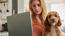 Frau checkt ihre Tierkrankenversicherung mit Cockapoo auf dem Schoß
