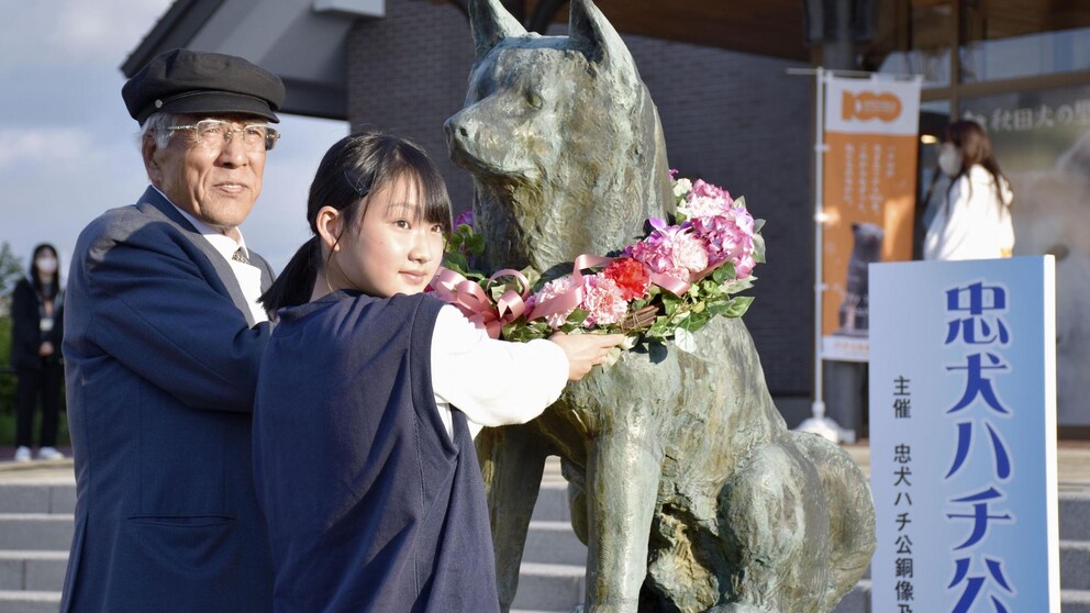 Zwei Japaner legen an der Statue von Hachiko einen Blumenkranz ab