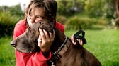 Mädchen mit Hund im Arm auf einem Feld