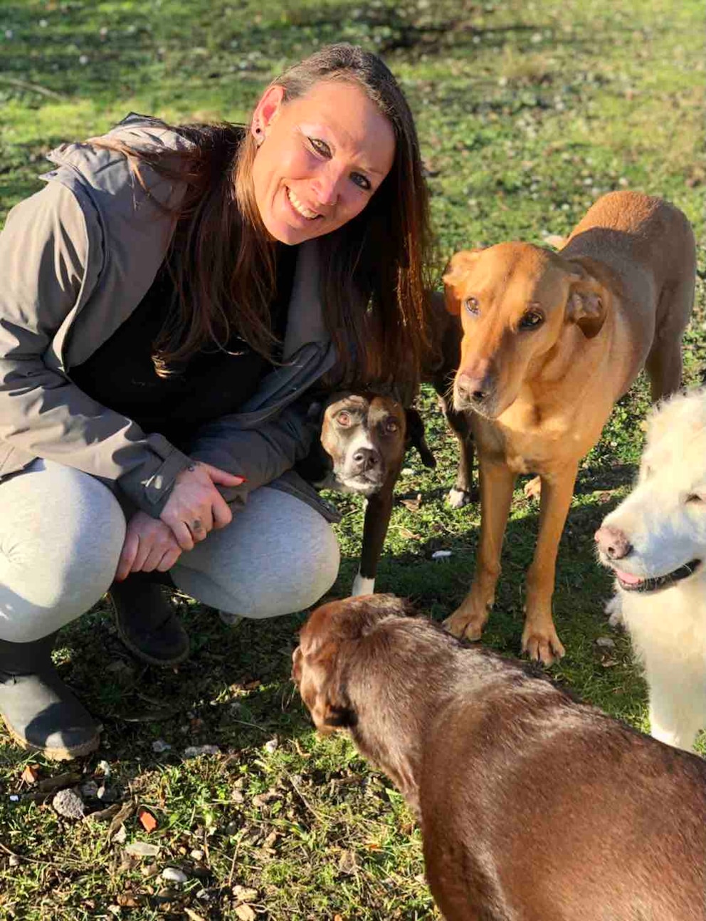 Hundetrainerin Désirée Scheller posiert mit vier Hunden auf einer Wiese. 