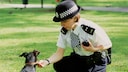 Polzeibeamtin in London beugt sich über einen Hund, um dessen Marke zu überprüfen