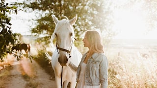 Frau führt ein Pferd auf die Weide.