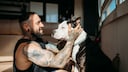 Ein Mann kuschelt mit seinem American Staffordshire Terrier.