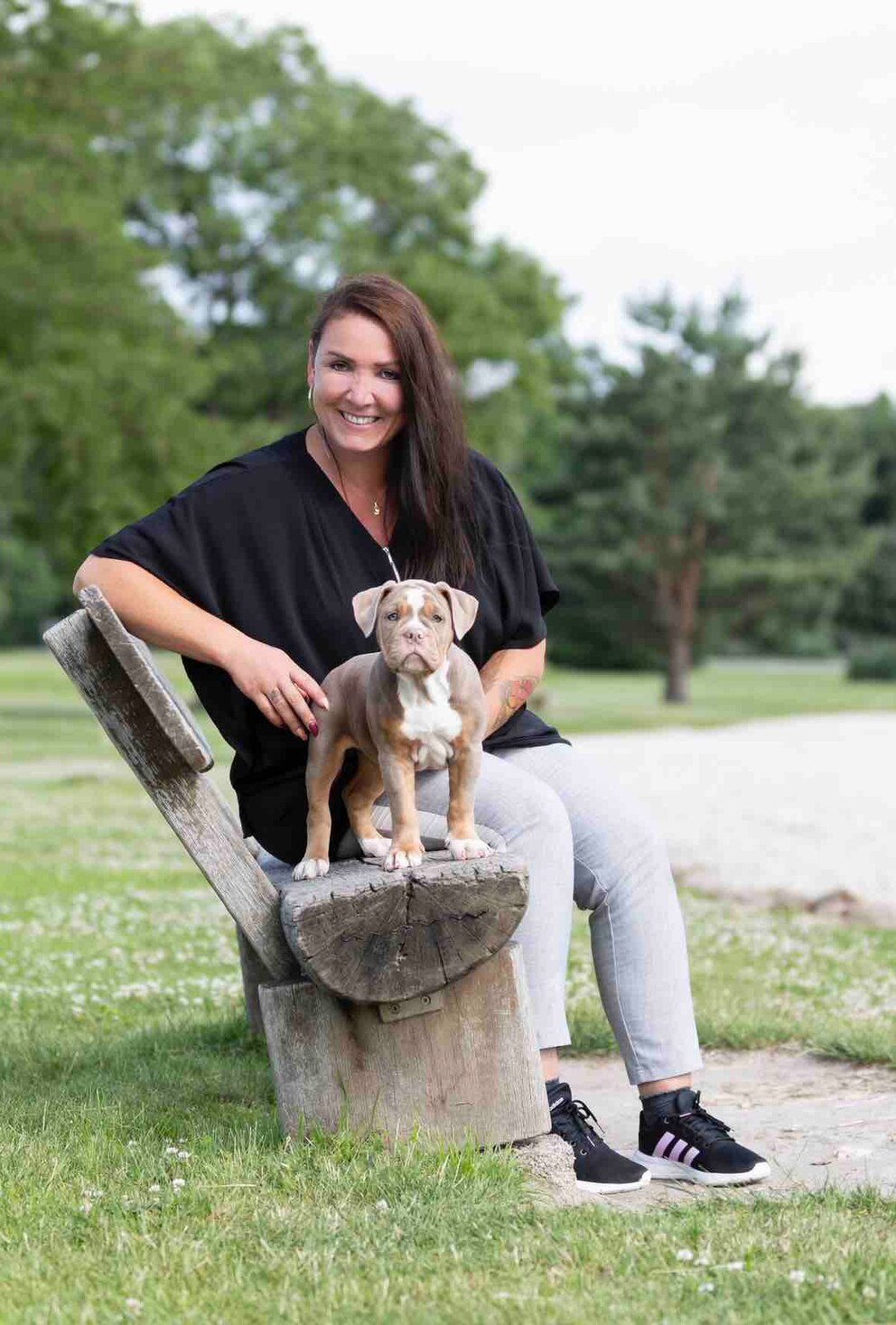 Hundetrainerin Désirée Scheller  posiert mit einem Welpen auf einer Bank. 