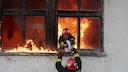 Feuerwehrleute retten eine Katze aus einem brennenden Haus
