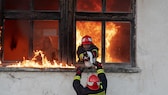 Feuerwehrleute retten eine Katze aus einem brennenden Haus