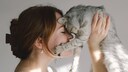 Frau dr&uuml;ckt ihren Kopf an den ihrer Katze, die ihr die Pfote ins Gesicht h&auml;lt