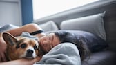 Frau lieg mit Hund zusammen im Bett