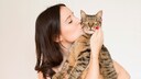 Frau h&auml;lt Katze im Arm und gibt ihr einen Kuss