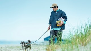 Man mit Hund hält Bücher im Arm