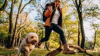 Frau ist mit ihrem Hund im Wald unterwegs