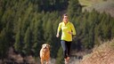 Eine Frau joggt mit ihrem Hund über eine Lichtung