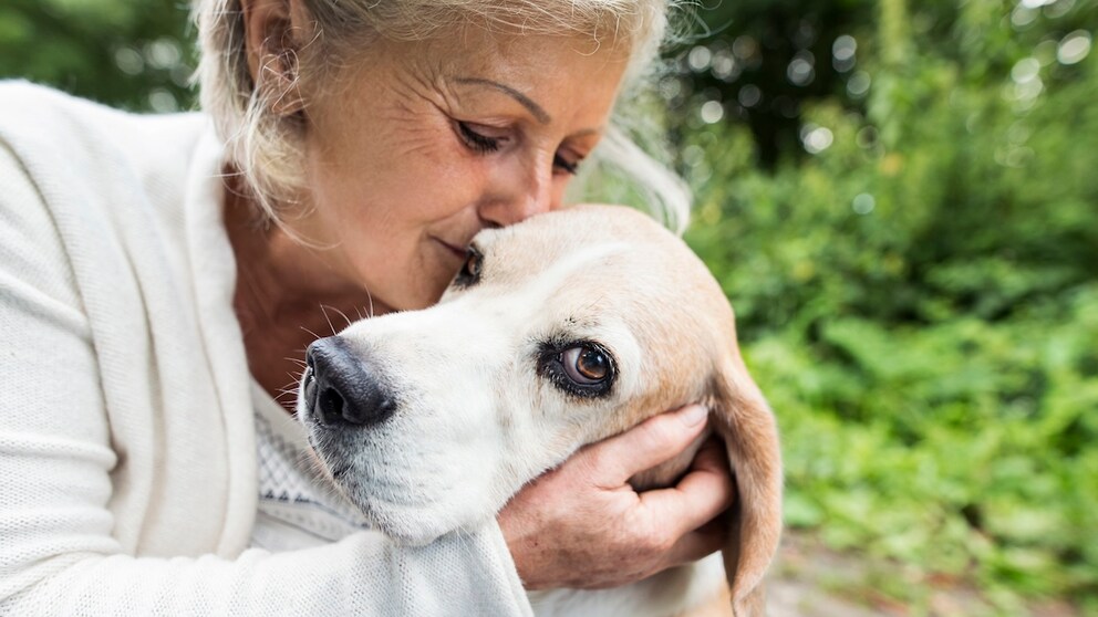 Ältere Frau kuschelt mit ihrem Hund