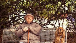 Älterer Mann und Cocker Spaniel auf Parkbank