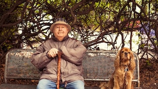 Älterer Mann und Cocker Spaniel auf Parkbank