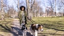 Frau geht mit ihren Hunden in einem Berliner Park an der Leine spazieren