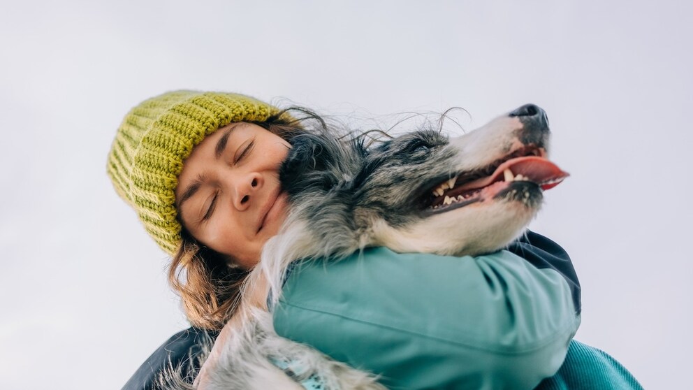 Frau umarmt ihren Hund