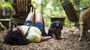 Frau liegt auf dem Boden mit angewinkelten Beinen während der Hund daneben steht