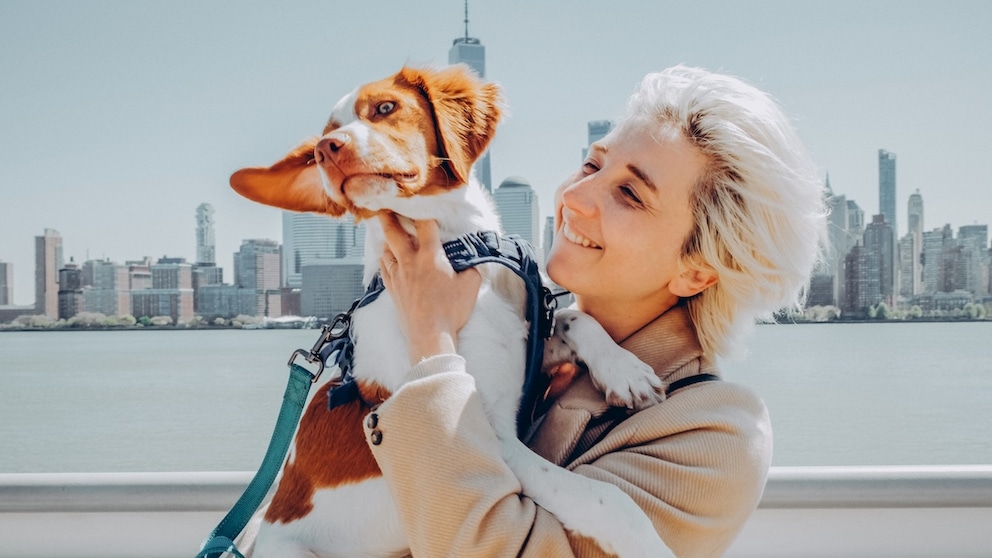 Frau vor der Skyline New-York mit Hund auf dem ARm
