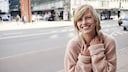 Lachende Frau auf Straße mit rosa Pullover