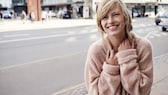 Lachende Frau auf Straße mit rosa Pullover