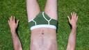 Mann mit Unterhose liegt im Gras