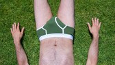 Mann mit Unterhose liegt im Gras