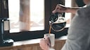 Mann gießt Kaffee in Tasse ein