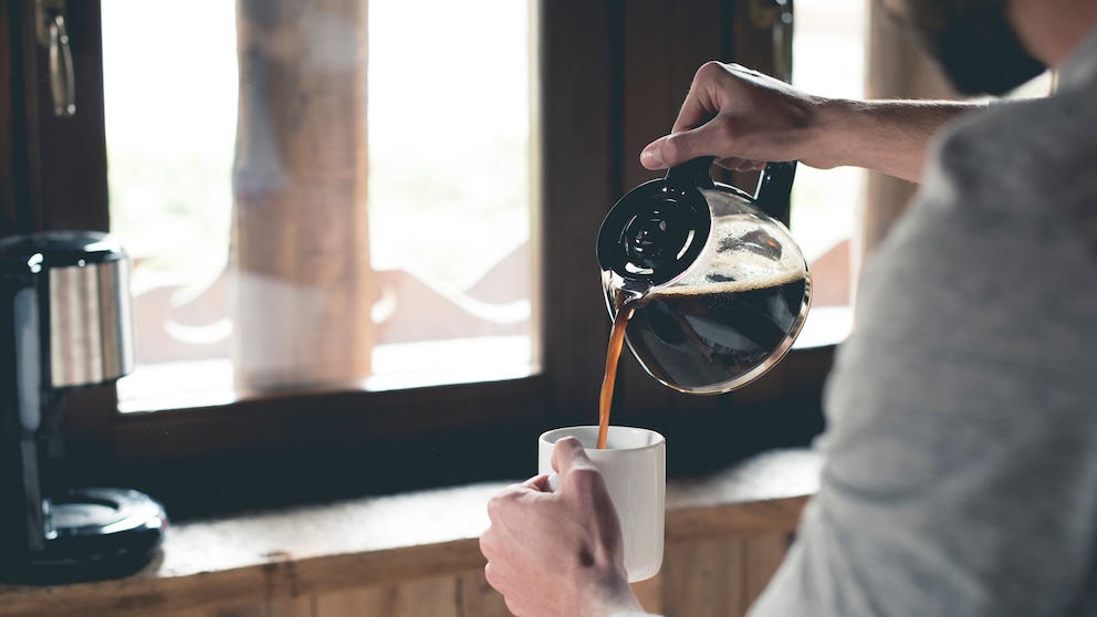 Mann gießt Kaffee in Tasse ein