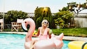 Frau mit Gummi-Flamingo im Pool