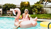 Frau mit Gummi-Flamingo im Pool