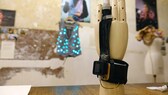 Ein Handmodel mit Fingerprothese steht auf einem Tisch in der Schneiderei für elektronische Textilien