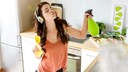 Young woman in kitchen cleaning and listening to music