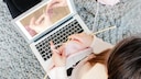 Frau strickt vor Laptop